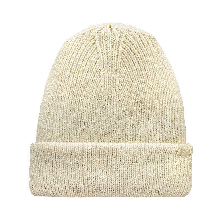 Displayed is a cream-colored knitted beanie, ribbed throughout, featuring a folded cuff with a tiny triangular tag.