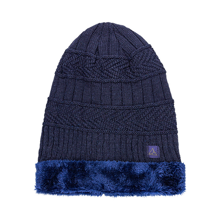 A navy blue heavy knit beanie with a detailed cable knit pattern, a ribbed fold-over cuff, and a band of fluffy blue faux fur. The beanie is finished with a small triangular logo on the cuff.