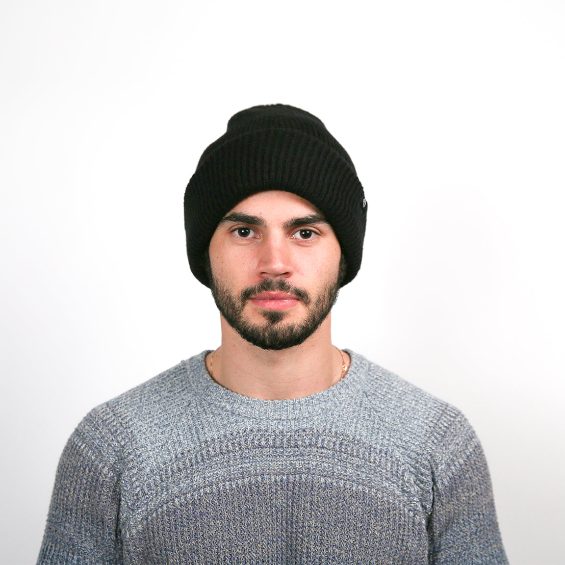 Displayed is a person wearing a classic knit beanie in solid black. The beanie has a ribbed texture with a cuffed brim, providing a snug and comfortable fit for a casual look.