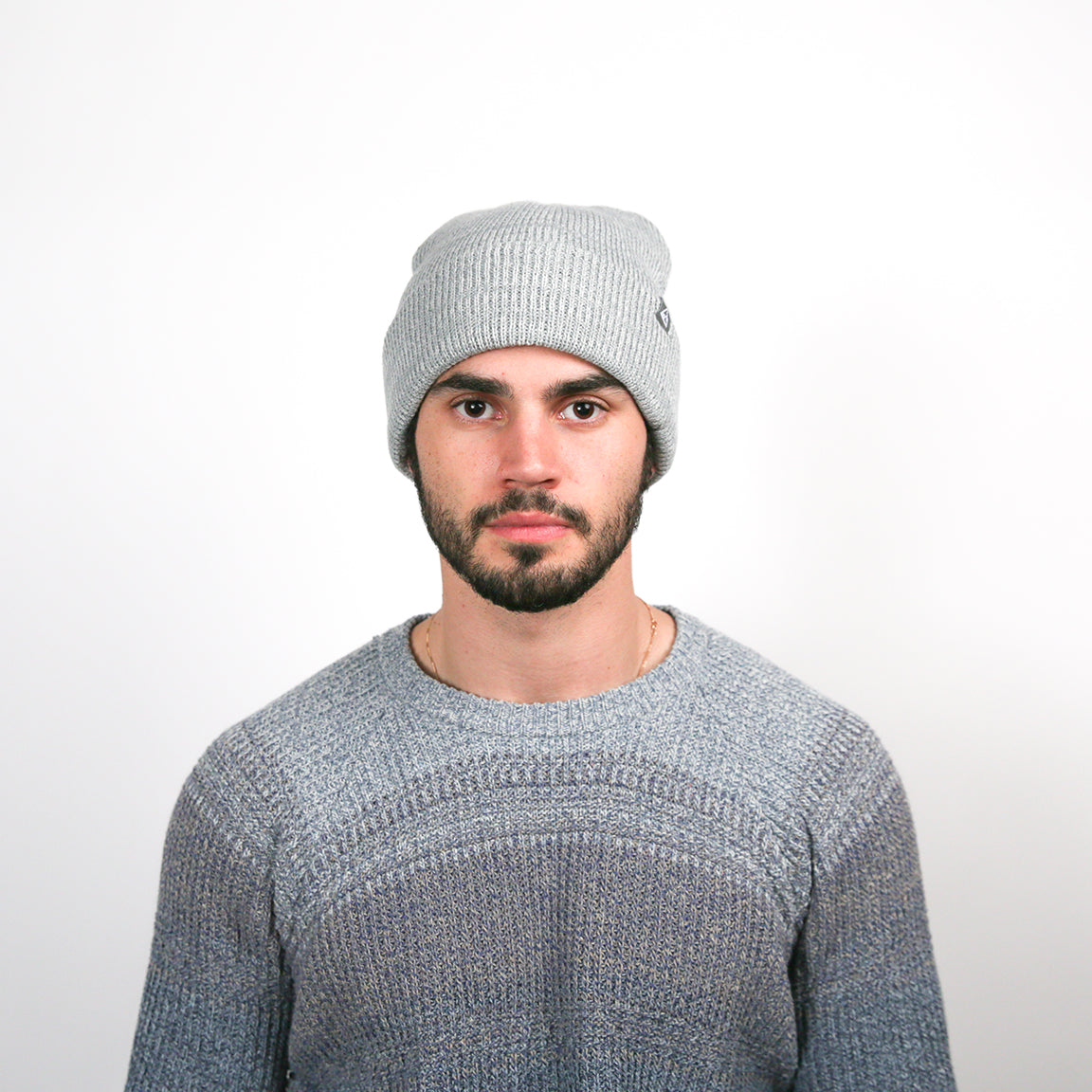 A model wearing a loosely fitted, light grey knit beanie with a subtle ribbed texture, providing a contemporary and easy-to-wear look.