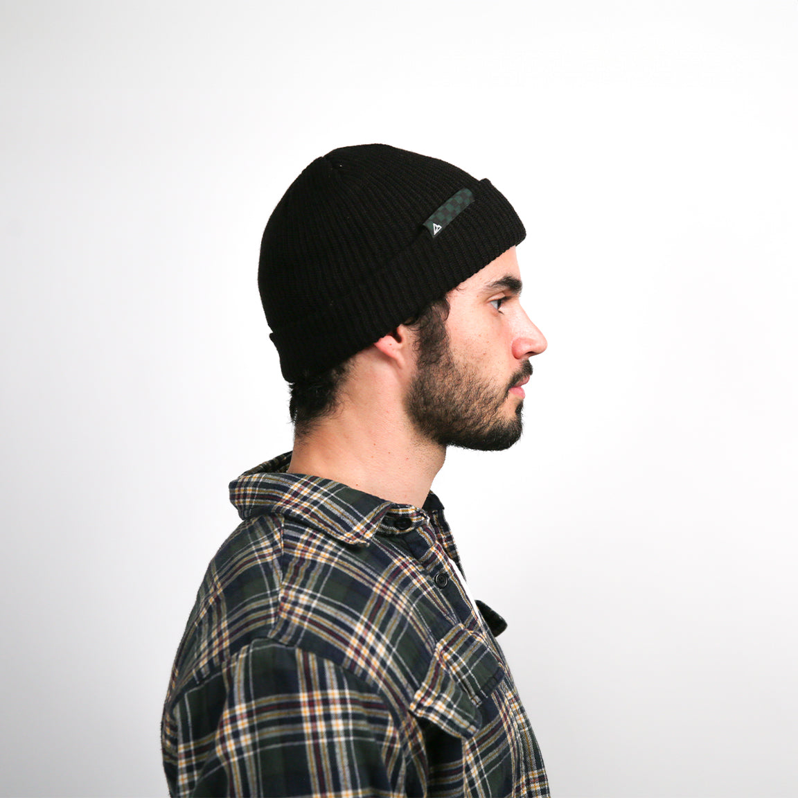 Here, the beanie is shown from the side with a green and black checkered logo patch, providing a slight variation in design while maintaining the overall look and feel.