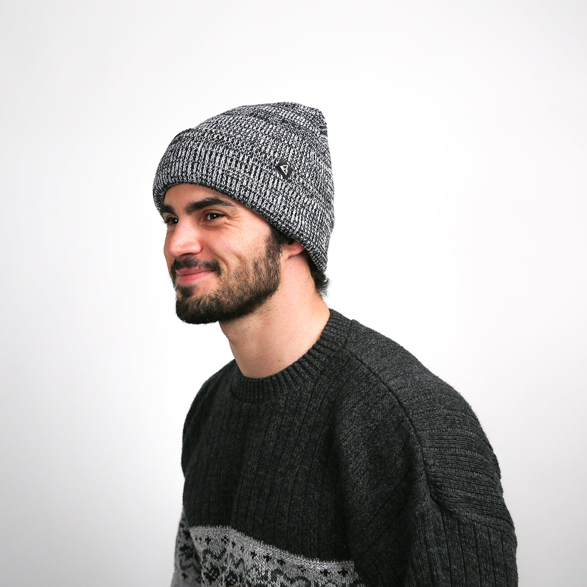The wearer is seen smiling, with the grey knit beanie styled to sit back on the head, enhancing the casual, comfortable vibe of the accessory.