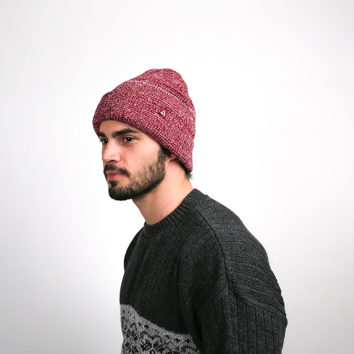 The model presents the beanie with a casual tilt, highlighting the easygoing nature of the piece, while the burgundy color serves as a vibrant accent.