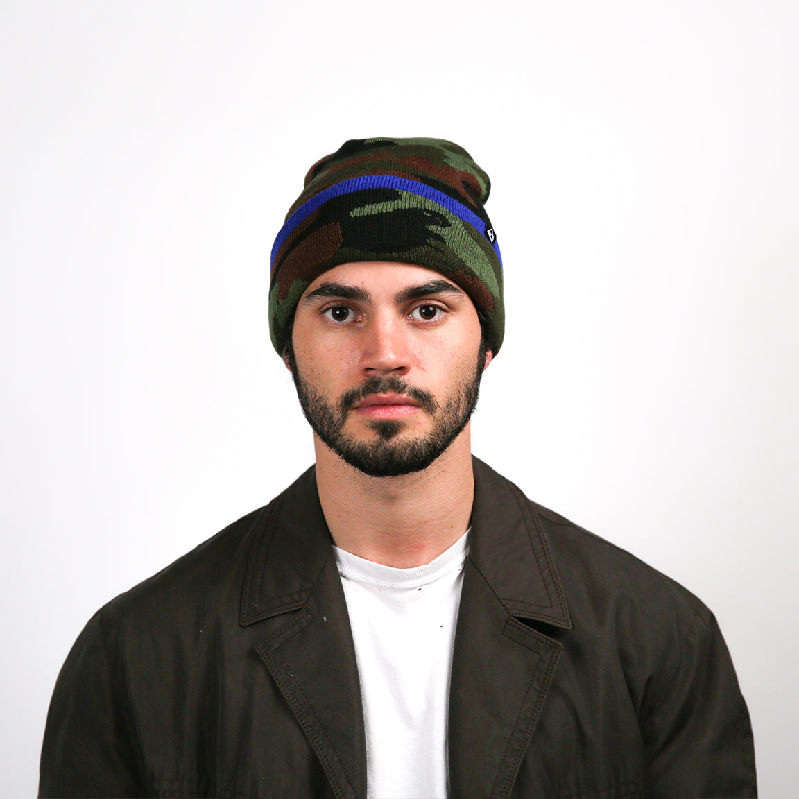 A knitted beanie with a camouflage pattern in dark green, navy blue, and brown, accented with a bright blue stripe. A small black triangular logo is stitched near the brim. The beanie is fitted snugly on the head with a bit of extra room at the top, suggesting a slightly slouchy style.